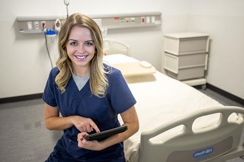 Nursing student poses in a hospital room.