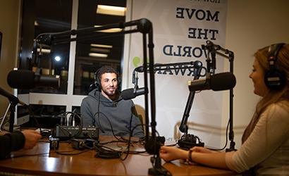 A student talks into the microphone in a podcast studio