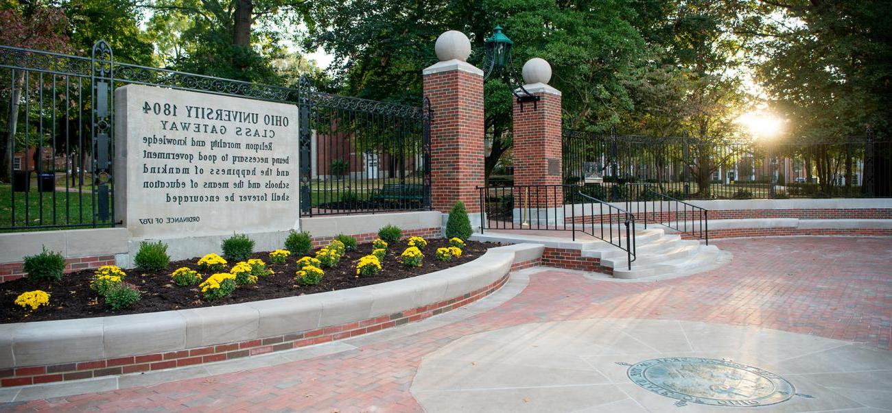 Class Gateway at Ohio University, lined with yellow flowers and a setting sun in the background